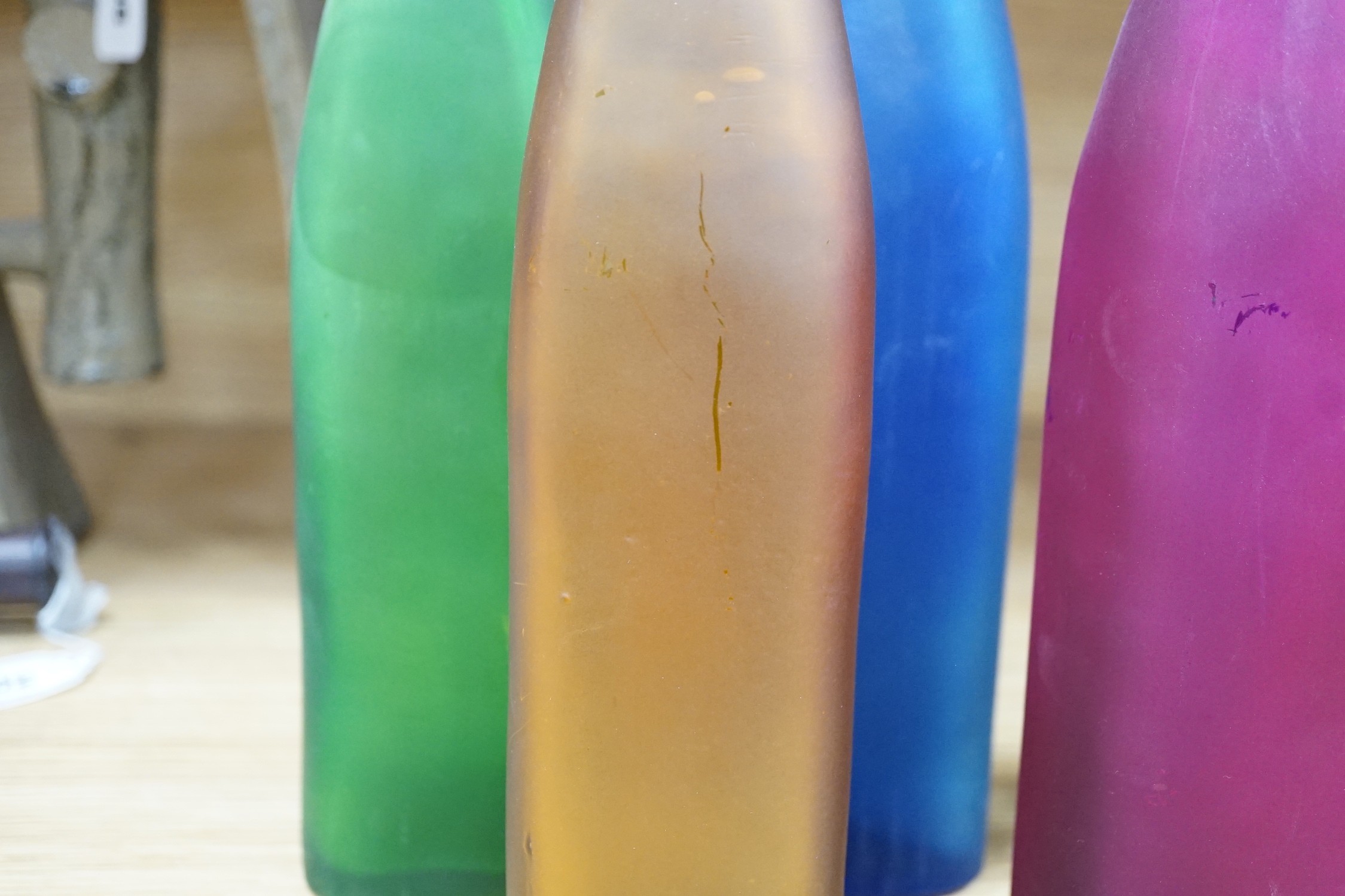 Five coloured glass bottle-neck vases, 42cms high